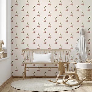 May include: A nursery room with a light pink wall covered in a pattern of watercolor cherries. A wooden bench with a white pillow sits in front of the wall. A wooden rocking horse and a round rug are on the wooden floor.
