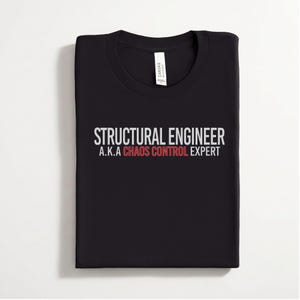 May include: A black crew neck t-shirt featuring the white text "STRUCTURAL ENGINEER" above the text "A.K.A" in white and "CHAOS CONTROL EXPERT" in red. The shirt has a white brand label inside the collar area, visible at the neckline.