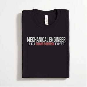 May include: A black crew neck t-shirt featuring the white text MECHANICAL ENGINEER and A.K.A, with the words CHAOS CONTROL EXPERT printed in red. The shirt has a white brand label inside the collar area, and the fabric is folded neatly.