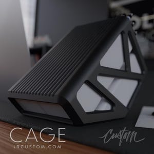 May include: Black hard drive case with a geometric design and a textured top. The case has the text "CAGE" and "iRCUSTOM.COM" printed on the bottom. The case is sitting on a black surface.