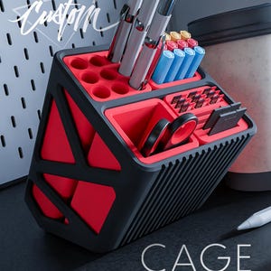 May include: A red and black geometric desktop organiser with multiple compartments for pens, pencils, and other office supplies. The organiser has a black and red striped pattern on the side. The text "CAGE ircustom.com" is printed on the bottom of the organiser.