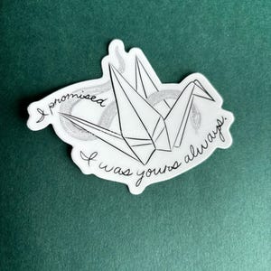 Puede incluir: Una grulla de origami blanca con una serpiente negra envuelta alrededor. El texto "I promised I was yours always." est&aacute; escrito alrededor de la grulla.