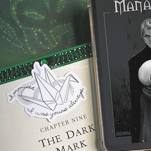 Puede incluir: Una gr&uacute;a de origami blanca con un dise&ntilde;o de serpiente blanco y negro. La gr&uacute;a est&aacute; sobre un libro con el texto "I promised I was yours always." y "Chapter Nine The Dark Mark".