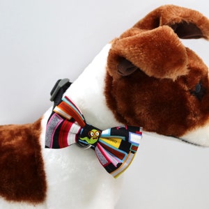 May include: A brown and white dog wearing a black bow tie with a colorful book pattern and a green worm with glasses graphic.