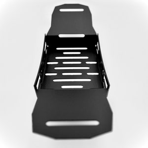 May include: A black metal tray with a rectangular shape and a series of horizontal cut-out slots. The tray has a handle-like design on each end and is set against a white background.