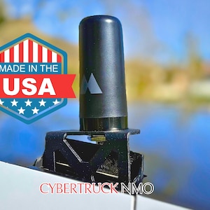 May include: A black antenna with a triangular logo on the side, mounted on a black bracket. The bracket is labeled "CYBERTRUCK NMO".