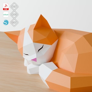 May include: A geometric papercraft cat in orange, white, and pink, lying down with its eyes closed. The cat is made of folded paper with a polygonal design. The image includes icons for PDF, SVG, DXF, and Cricut file formats.