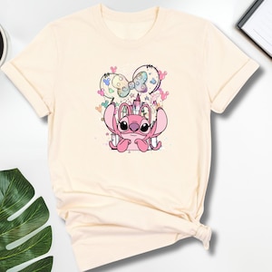 a t - shirt with a cartoon mouse on it next to a cup of coffee