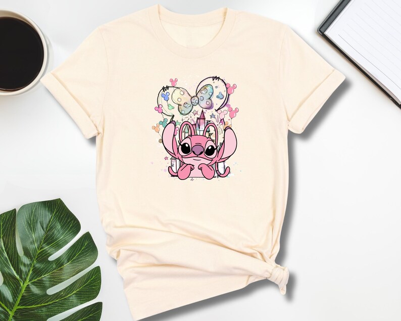 a t - shirt with a cartoon mouse on it next to a cup of coffee