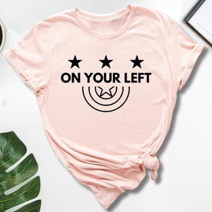 a pink shirt that says on your left
