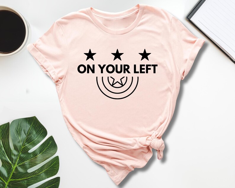 a pink shirt that says on your left