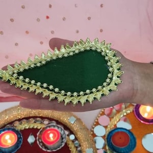 May include: A green and gold decorative tray with a beaded border. The tray is filled with small mirrors and candles.