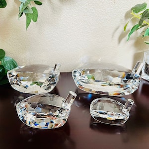 May include: Four clear crystal golf ball divots of varying sizes. The divots are all shaped like a golf ball and have a small hole in the top.