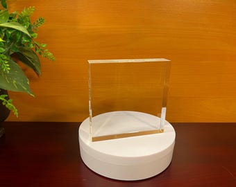 May include: A clear glass plaque on a white round pedestal. The plaque is blank and ready for engraving.