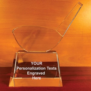 May include: A clear glass golf club trophy with a base that says "YOUR Personalization Texts Engraved Here".