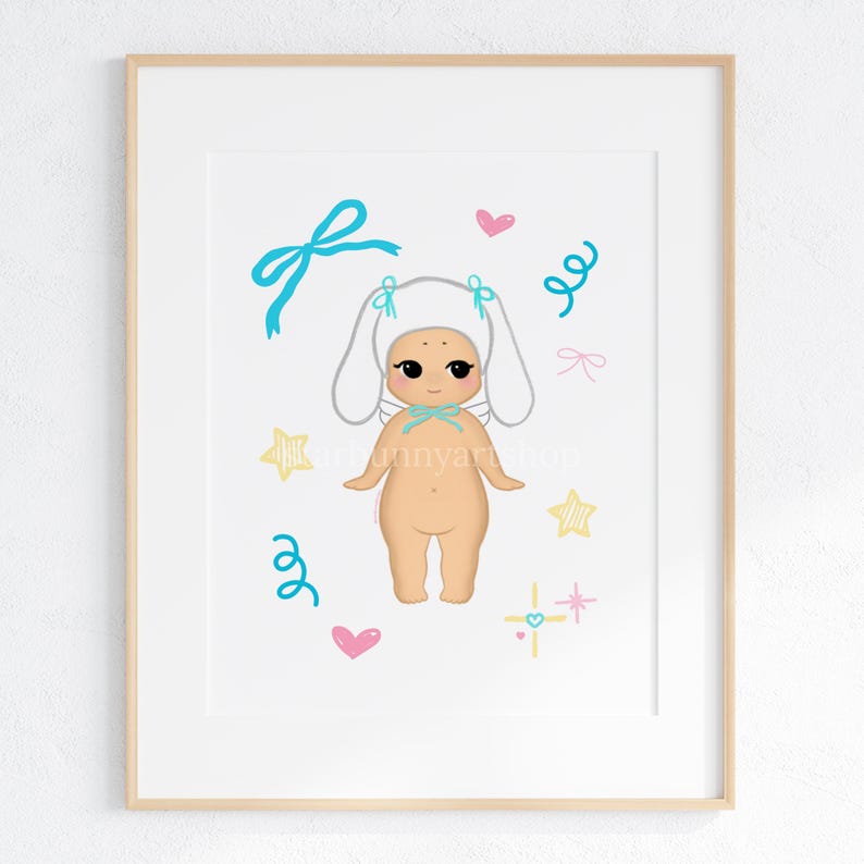 May include: A framed art print featuring a cartoon illustration of a nude figure wearing a white bunny ear hat and a blue bow. The artwork includes blue bows, pink hearts, yellow stars, and blue swirls. The print is in a wooden frame.