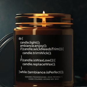 May include: A brown glass candle jar with a black label that reads "do { candle.light(); ambiance.enjoy(); if (candle.wickNeedsTrim()) { candle.trimWick(); if (candle.isWaxLow()) { candle.replaceWax(); } while (ambiance.isPerfect()); } SARABELTRANDESIGNS | ECO-FRIENDLY | HAND POURED VEGAN SOY WAX". The candle is lit and the wax is melting.