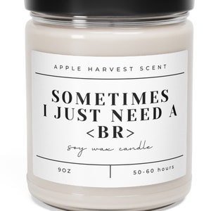 May include: A soy wax candle in a clear glass jar with a black lid. The label reads "APPLE HARVEST SCENT" and "SOMETIMES I JUST NEED A <BR>". The candle is 9 oz and has a burn time of 50-60 hours.