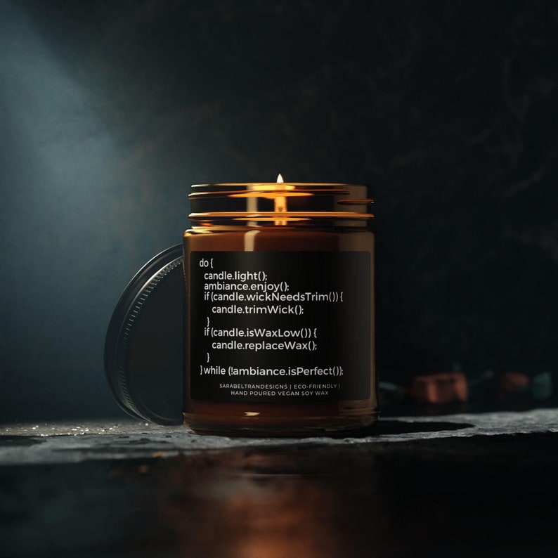 May include: A brown glass candle jar with a black label that reads "do { candle.light(); ambiance.enjoy(); if (candle.wickNeedsTrim()) { candle.trimWick(); if (candle.isWaxLow()) { candle.replaceWax(); } while (ambiance.isPerfect()); } SARABELTRANDESIGNS | ECO-FRIENDLY | HAND POURED VEGAN SOY WAX". The candle is lit and the wax is melting.