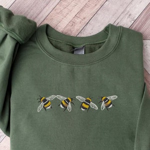 May include: A green sweatshirt with a row of five embroidered bumblebees in yellow and black.