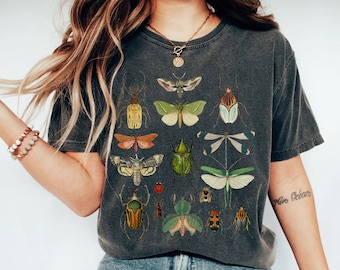 May include: A dark gray t-shirt with a vintage illustration of various insects, including beetles, butterflies, and dragonflies. The insects are depicted in a realistic style with intricate details.