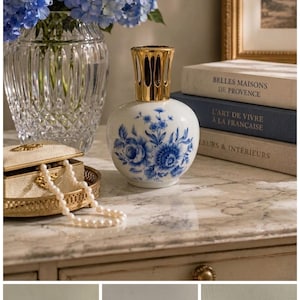 May include: A white ceramic fragrance lamp with a rounded body featuring blue floral patterns and a gold-toned metal crown top. The lamp includes a separate metal cap and a fabric wick, shown both assembled and disassembled in multiple views.