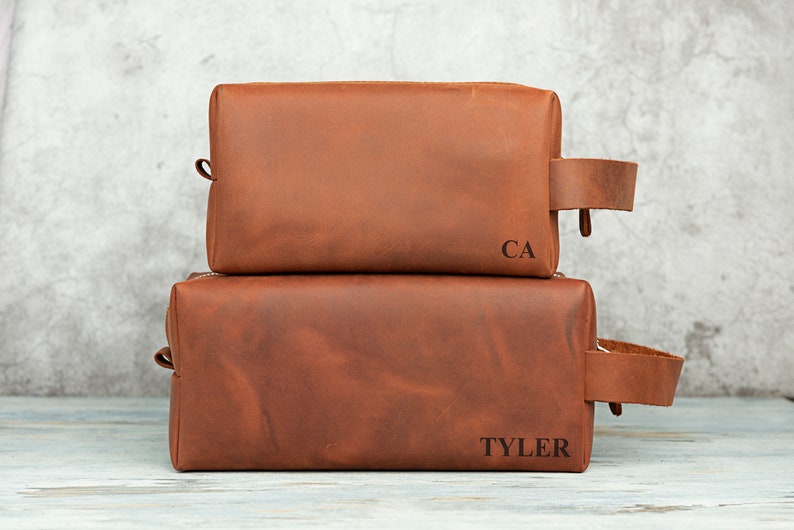 Pu&ograve; includere: Due trousse da toilette in pelle marrone con le iniziali "CA" e "TYLER" incise.