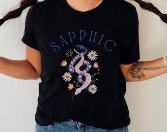 May include: Black t-shirt with a graphic of two purple snakes intertwined with pink and orange flowers. The text "SAPPHIC" is printed in purple above the snakes.