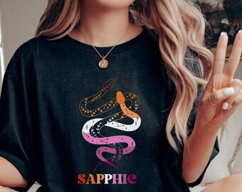 May include: A black t-shirt with a graphic of a snake with a lesbian pride flag color scheme and the word "sapphic" printed below it.