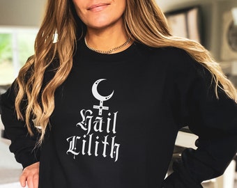 Peut inclure: Sweat-shirt noir avec un motif blanc représentant une lune croissante, une croix et le texte "Hail Lilith".