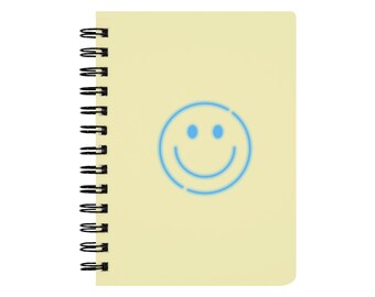 May include: A spiral-bound notebook with a light yellow cover. A blue outline of a smiley face is centered on the cover. The notebook's binding is black.