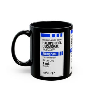 May include: Black ceramic mug featuring a label with the text "HALOPERIDOL DECANOATE INJECTION 50 mg/mL". The mug has a curved handle and a white label with blue text. The mug is a standard 11 oz size.