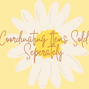 May include: A white daisy with a yellow center on a yellow background. The text "Coordinating Items Sold Separately" is written in brown cursive.