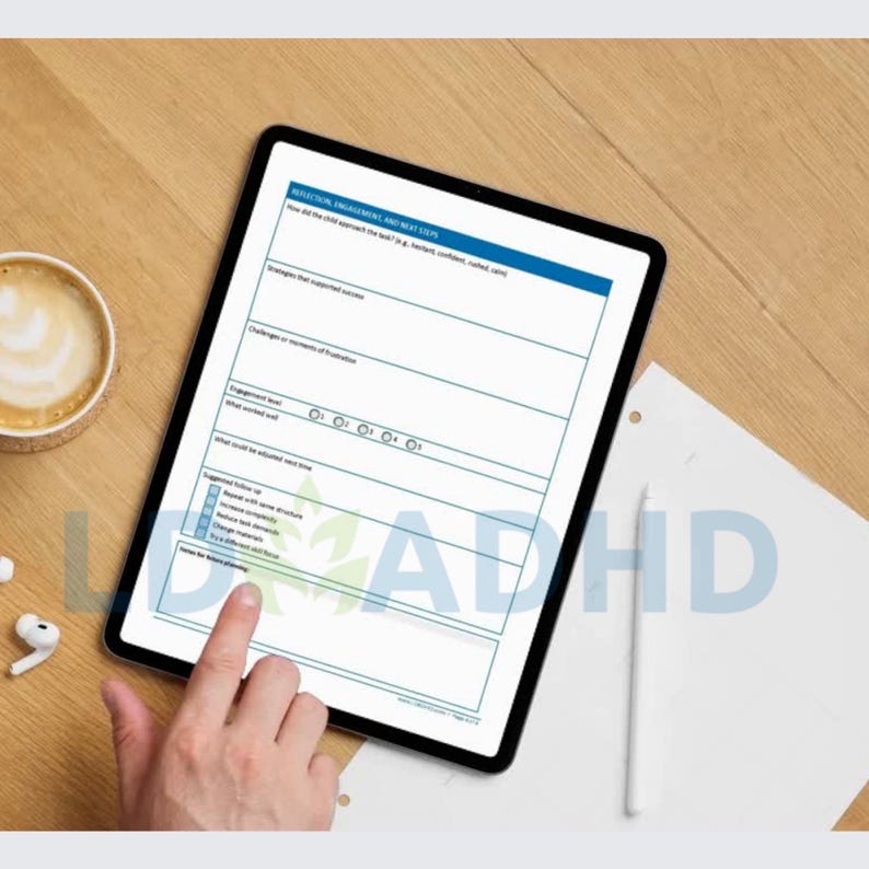 Peut inclure: Une tablette num&eacute;rique affichant un formulaire avec des sections bleues et blanches, avec le texte "REFLECTION, ENGAGEMENT, AND NEXT STEPS" en haut. Une main touche l'&eacute;cran. Une tasse de caf&eacute; et des &eacute;couteurs sans fil sont sur la surface en bois.