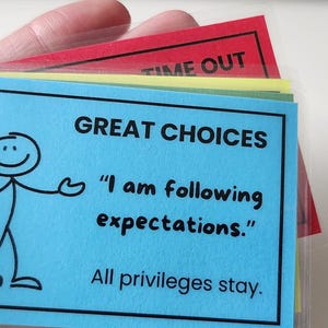 May include: A set of colorful cards on a metal ring. The blue card reads "GREAT CHOICES" with a stick figure and the text "I am following expectations. All privileges stay." A red card with "TIME OUT" is visible.