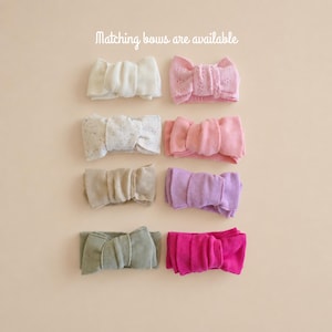 May include: Eight fabric headbands arranged in two columns, featuring various colors including white, light pink, speckled cream, solid pink, beige, lavender, sage green, and magenta. The text "Matching bows are available" is at the top.