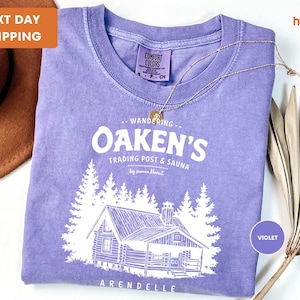 a purple shirt with a picture of a cabin on it
