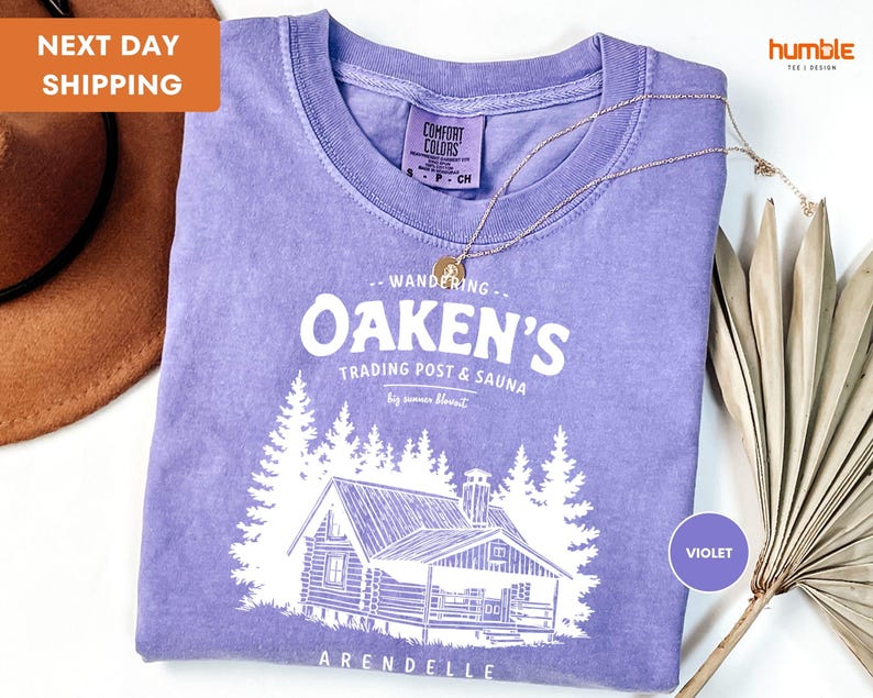 a purple shirt with a picture of a cabin on it