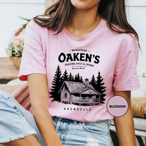 a woman wearing a pink shirt with a picture of a cabin on it