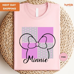 A pink t-shirt with a graphic design featuring Minnie Mouse's ears and bow, along with a pink heart pattern.