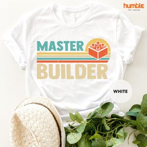 a t - shirt that says master builder next to a hat
