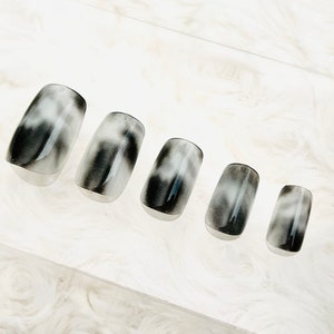May include: Set of six black and white ombre press-on nails. The nails are short and square shaped.