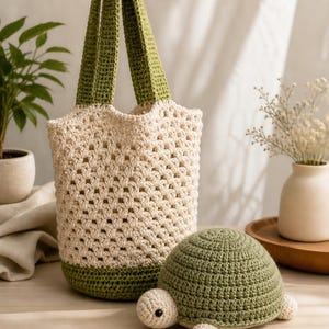 May include: A crocheted tote bag with olive green handles and base, and a cream-colored body. A crocheted turtle with a green shell and cream-colored head and feet sits next to the bag. The items are on a wooden surface.