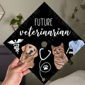Puede incluir: Un gorro de graduación negro con el texto "FUTURE veterinarian" en blanco. El gorro presenta un estetoscopio, una huella de pata, un perro, un gato y un símbolo médico con alas.