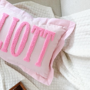 Peut inclure: Un oreiller rose avec le mot "LOVE" brod&eacute; en rose sur un fond blanc.
