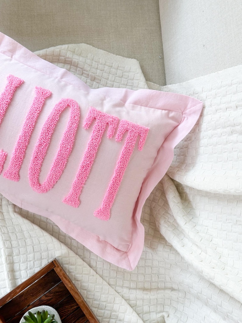 Peut inclure: Un oreiller rose avec le mot "LOVE" brod&eacute; en rose sur un fond blanc.