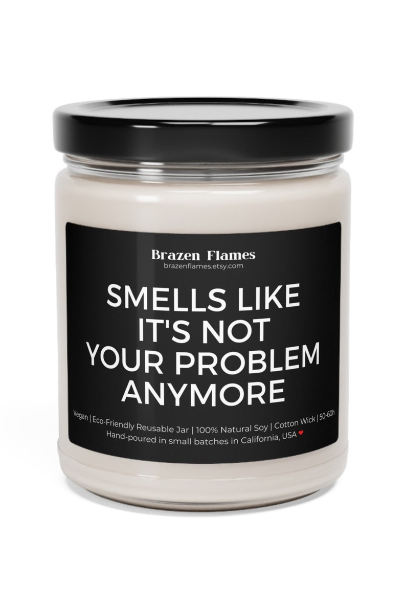 Puede incluir: Vela en tarro de cristal transparente con tapa negra y etiqueta negra. La etiqueta dice "SMELLS LIKE IT'S NOT YOUR PROBLEM ANYMORE" en texto blanco. La vela est&aacute; hecha con cera de soja natural y una mecha de algod&oacute;n.