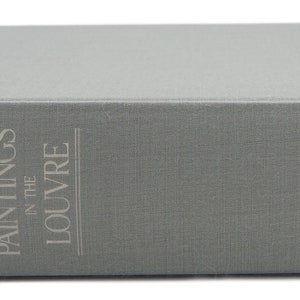 May include: A gray hardcover book with the title "Paintings in the Louvre" by John Rewald. The book is published by Harry N. Abrams, Inc., New York.