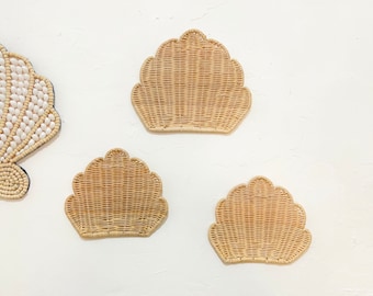 May include: Three woven wicker seashell wall decor pieces in various sizes. The shells are a light brown color and have a textured woven pattern.