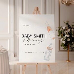 Pode incluir: Um cartaz de boas-vindas para um chá de bebê com o texto "Baby Smith is brewing ETA 58 days... 26.08.2024 #babysmith24" e ilustrações de uma garrafa e uma mamadeira.